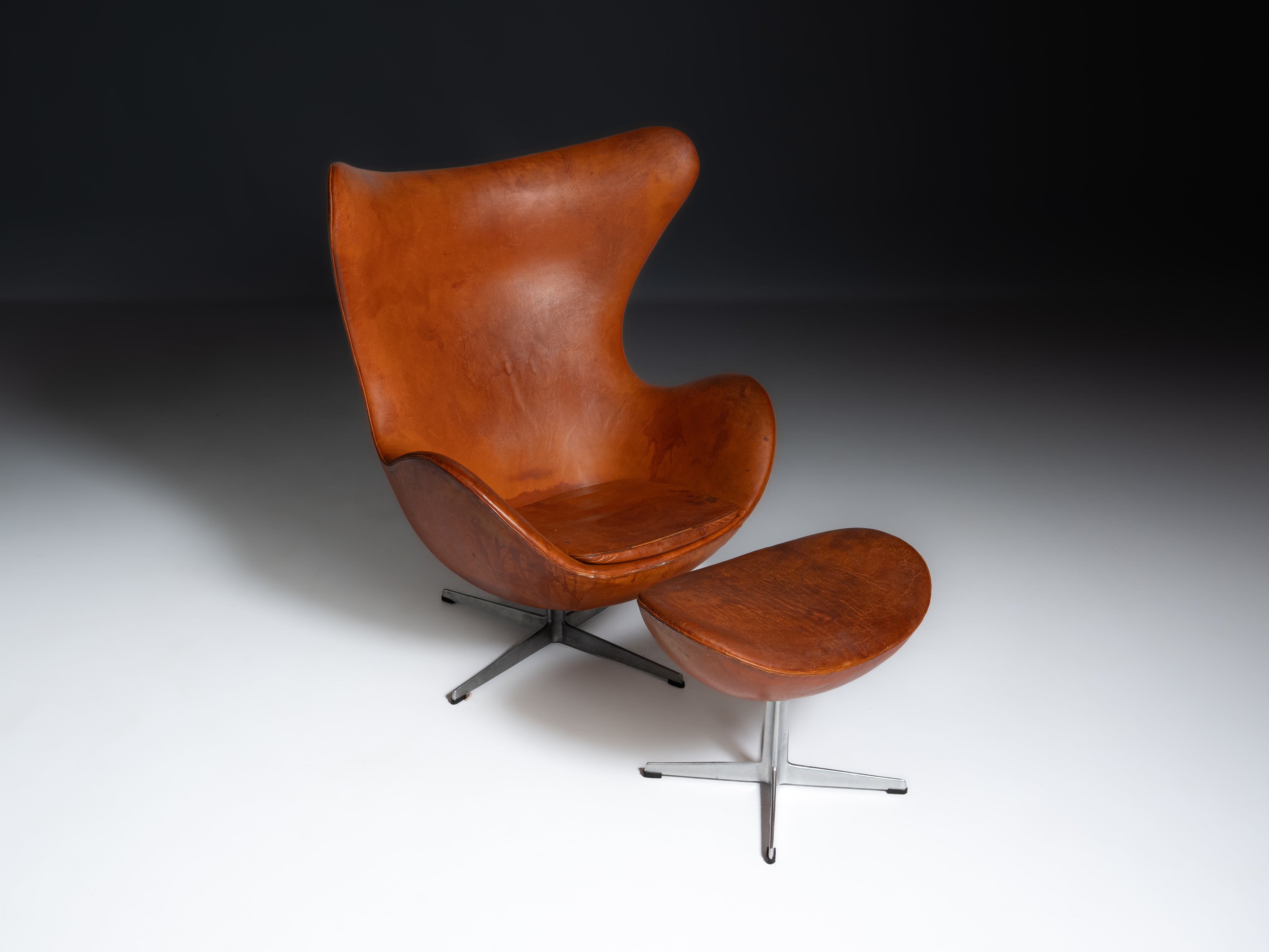 Egg Chair com banco de apoio, em pele cor de conhaque, design de Arne Jacobsen para a Fritz Hansen, Dinamarca, 1966. Marcada no fundo